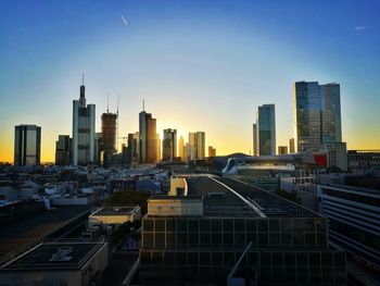 Modern buildings in city against clear sky during sunset