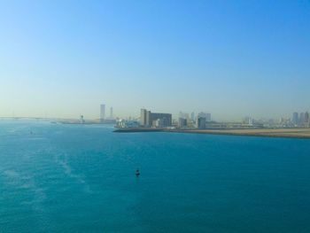 View of sea and buildings against blue sky