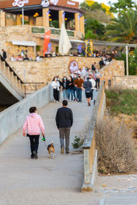 Rear view of people walking on footpath in city