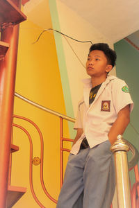 Boy looking away while standing against wall