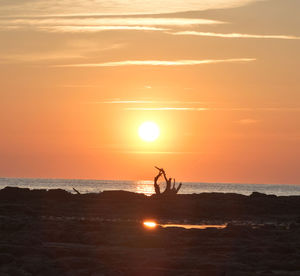 Silhouette people at beach against sky during sunset