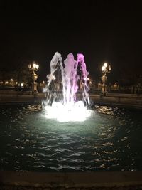 Illuminated fountain in city at night