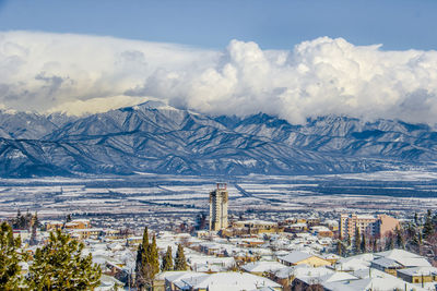 Aerial view of cityscape and mountains against sky during winter