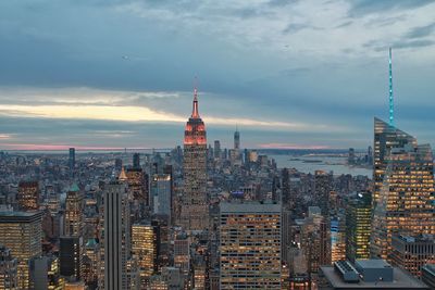 Buildings in city against cloudy sky during sunset