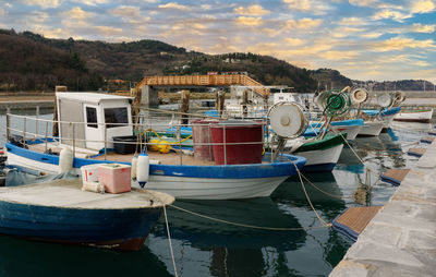 Fishing boats moored at harbor against sky