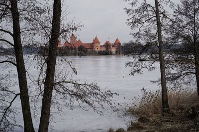 Scenic view of lake by building against sky during winter