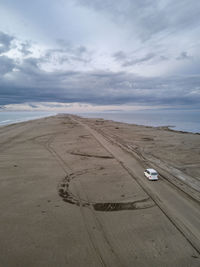 Van driving a long infinite sandy road