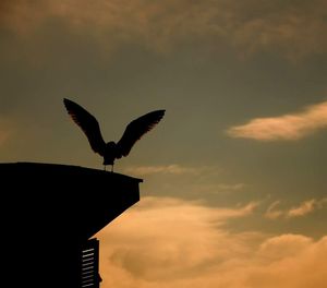 Low angle view of bird perching on tower