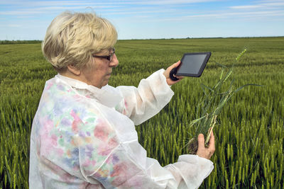 Rear view of woman using mobile phone on field