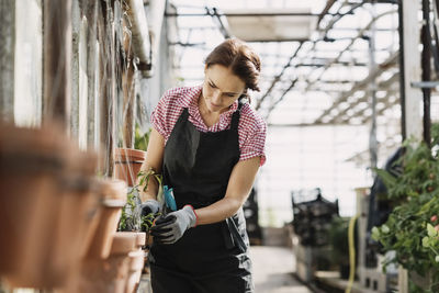 Young woman looking up while standing on potted plant
