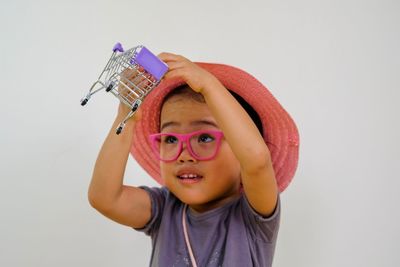 Portrait of cute boy holding camera over white background