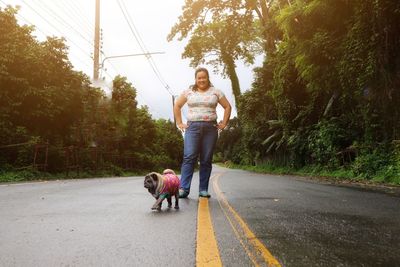 Woman with dog standing on road