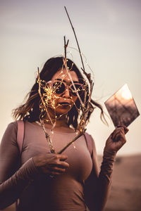 Midsection of woman holding umbrella against sky during sunset