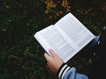 Midsection of person holding book on field