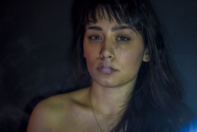 Close-up portrait of beautiful woman against black background