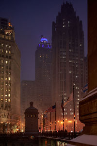 Low angle view of illuminated buildings against sky at night