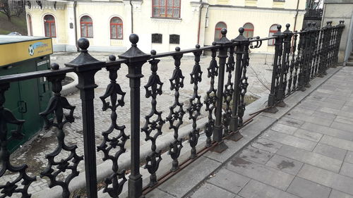 People on railing by street against buildings in city