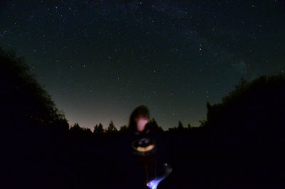 Silhouette woman photographing against clear sky at night