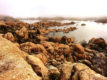 Rocks by sea against clear sky