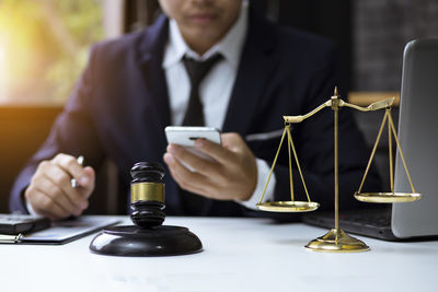 Midsection of man holding wine glass on table