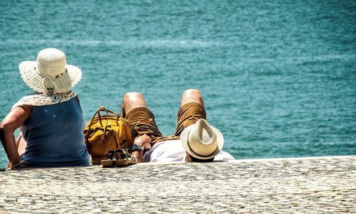 Rear view of couple relaxing at beach on sunny day