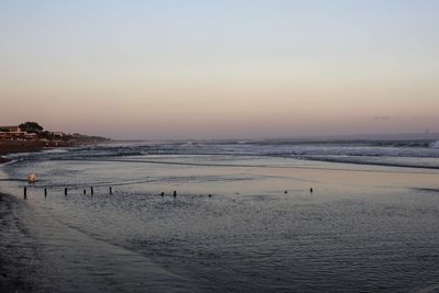 Scenic view of beach against sky at sunset