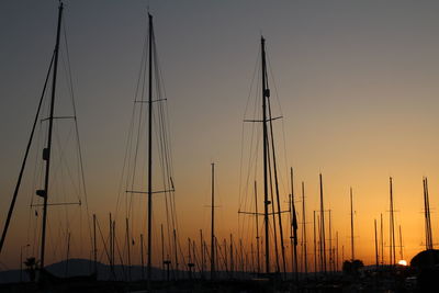 Silhouette sailboats on harbor against sky at sunset