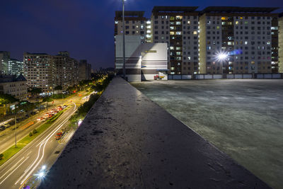 Illuminated street amidst buildings in city at night