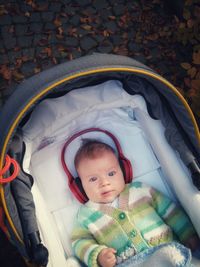 High angle portrait of cute baby boy listening music while lying in stroller