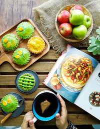 Cropped image of hands holding drink and desserts on table