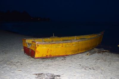 Boat moored on beach against sky