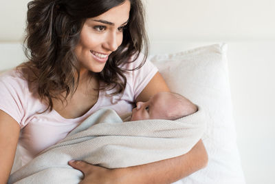 Portrait of a smiling young woman lying on bed