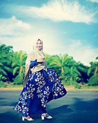 Woman with umbrella standing against the sky