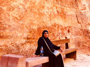 Portrait of a smiling young woman standing against brick wall
