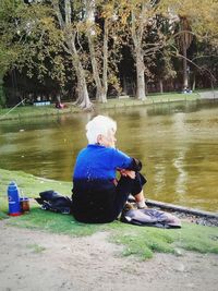 Rear view of woman sitting by lake