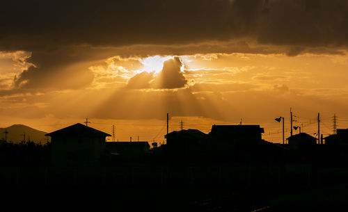 Silhouette of buildings against cloudy sky during sunset