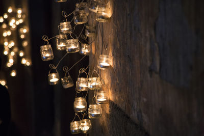 Illuminated tea light candles hanging on wall at home