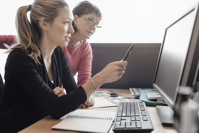 Businesswomen discussing over computer at desk in office