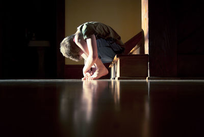 Sad boy hugging knees while sitting on steps