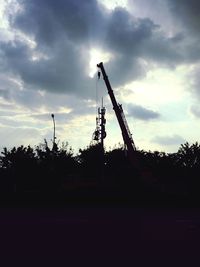 Low angle view of crane against cloudy sky