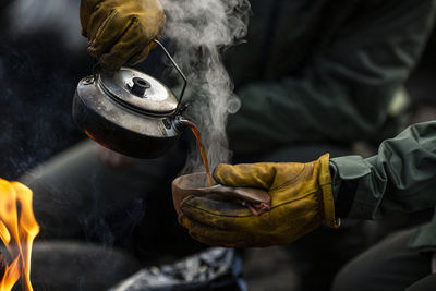 Hands pouring hot coffee from kettle