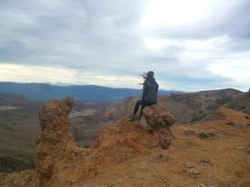 Man standing on rock against sky