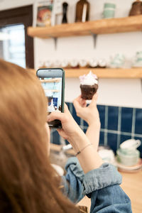 Midsection of woman photographing with mobile phone