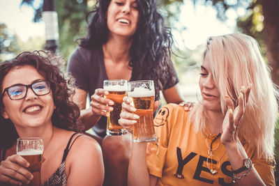 Portrait of happy young woman drinking glasses