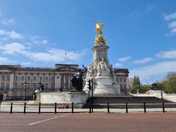 Statue of historical building in front of buckingham palace against cloudy sky