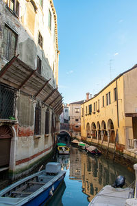 Canal by buildings in city against sky