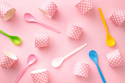 High angle view of cupcake holders and spoons on pink table