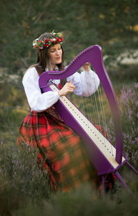 Young woman playing harp at forest