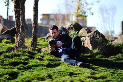 Man reading book while lying down on field