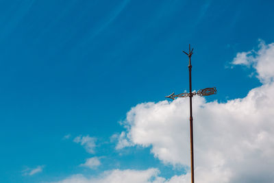 Low angle view of weather vane against sky